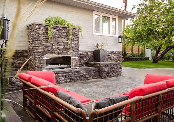 Outdoor living space with poured concrete patio and stone fireplace structure 