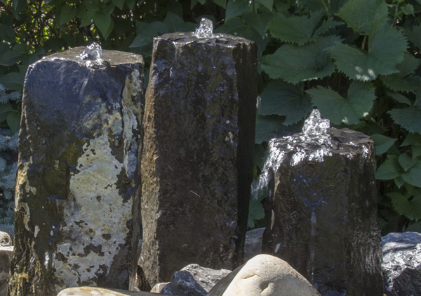 Tall stone water feature display with bubblers and cascading water 