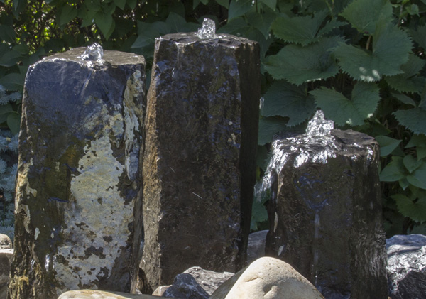Tall stone water feature display with bubblers and cascading water